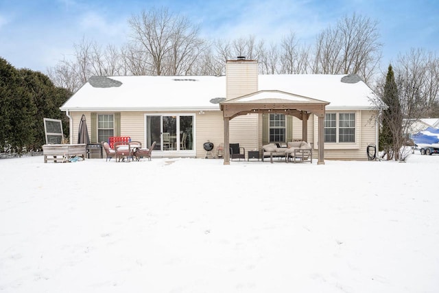 snow covered back of property featuring a gazebo and an outdoor living space