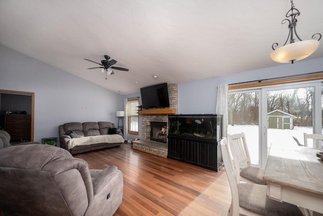 living room with a fireplace, wood-type flooring, vaulted ceiling, and ceiling fan