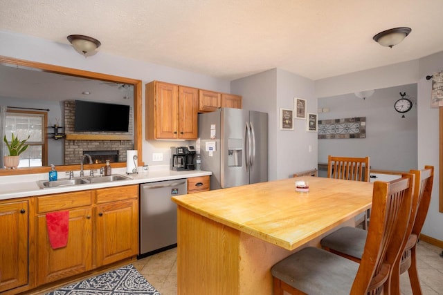 kitchen with appliances with stainless steel finishes, sink, butcher block countertops, a kitchen island, and a breakfast bar area