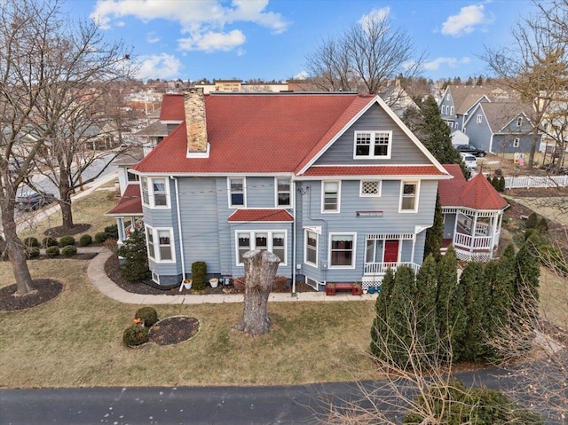 rear view of property with covered porch and a yard