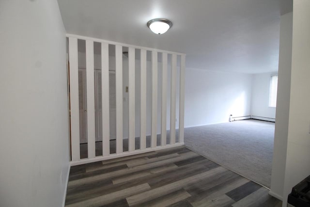 unfurnished room featuring baseboard heating and dark hardwood / wood-style floors