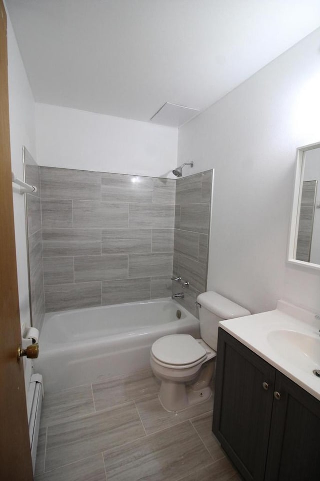 full bathroom with baseboard heating, tiled shower / bath, vanity, and toilet