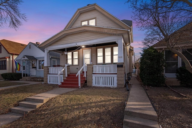 view of front of property with covered porch and a lawn