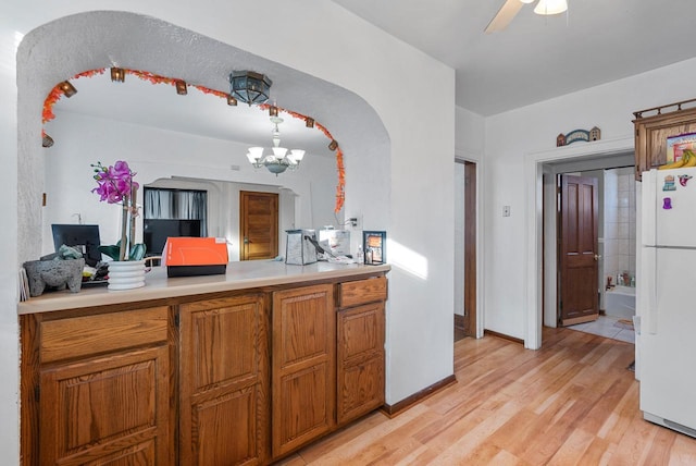 kitchen with white fridge, pendant lighting, ceiling fan with notable chandelier, and light wood-type flooring