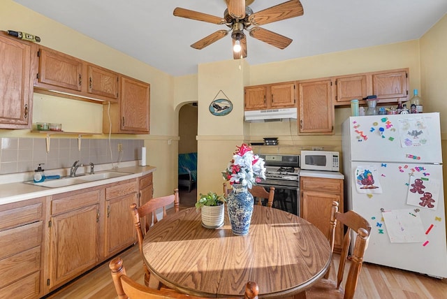 kitchen with decorative backsplash, white appliances, light hardwood / wood-style floors, and sink