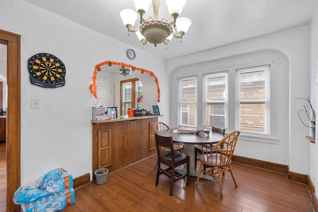 dining space with hardwood / wood-style flooring and a notable chandelier