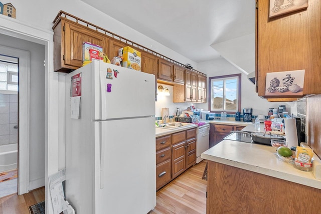 kitchen with light wood-type flooring, white appliances, and sink