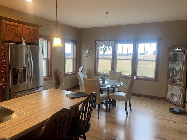 dining room with light wood-type flooring, a wealth of natural light, and a chandelier