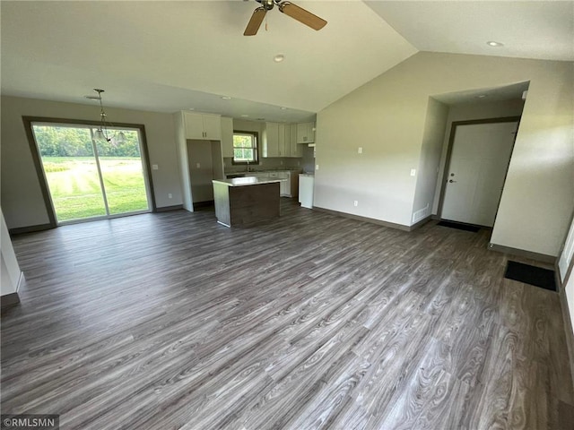 unfurnished living room featuring ceiling fan, dark hardwood / wood-style floors, sink, and vaulted ceiling