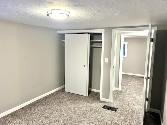 unfurnished bedroom featuring carpet, a textured ceiling, and a closet