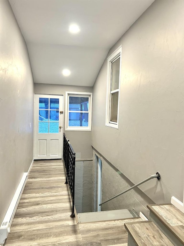 stairs featuring lofted ceiling and a baseboard heating unit