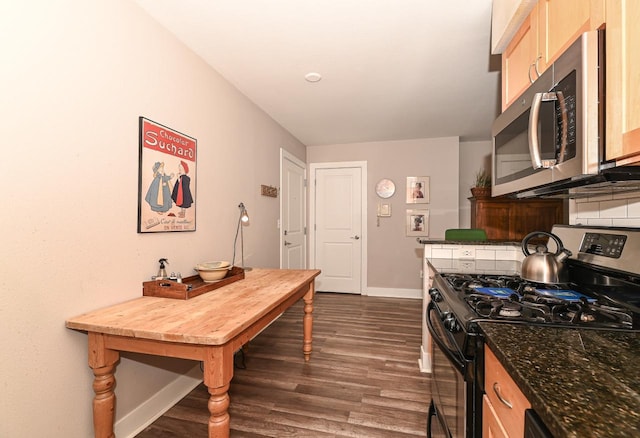 kitchen with black gas range, backsplash, light brown cabinets, and dark wood-type flooring