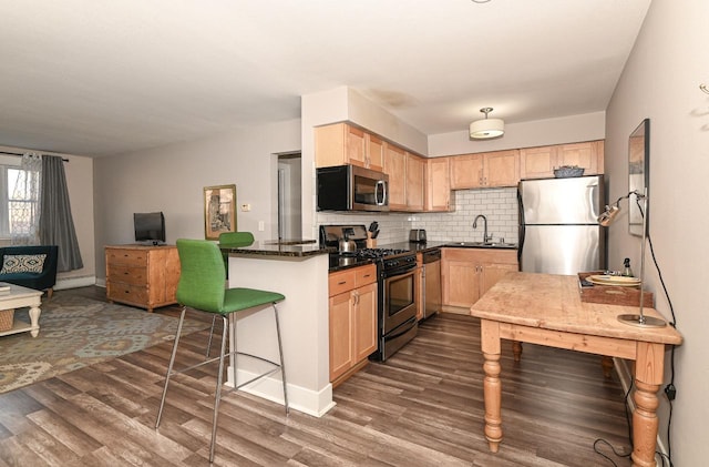 kitchen with sink, light brown cabinets, dark stone countertops, decorative backsplash, and appliances with stainless steel finishes