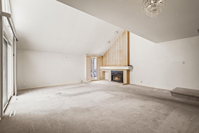 unfurnished living room featuring vaulted ceiling, a fireplace, light carpet, and a chandelier