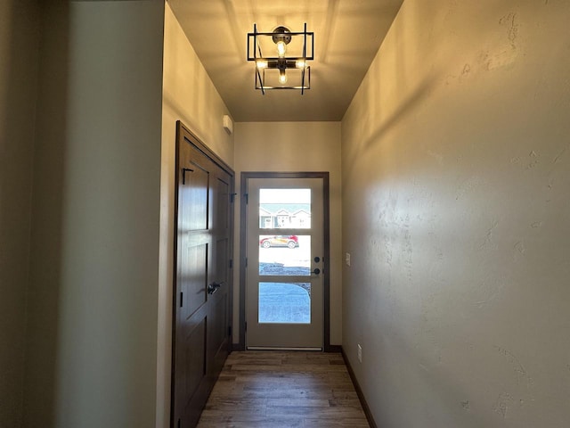 doorway to outside with a chandelier and hardwood / wood-style floors