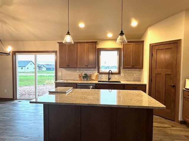 kitchen featuring decorative backsplash, pendant lighting, light stone countertops, and sink