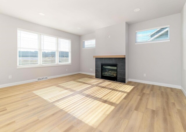 3620 Angelus Way, Cross Plains, WI 53528 - unfurnished living room with a tile fireplace, baseboards, light wood finished floors, and visible vents