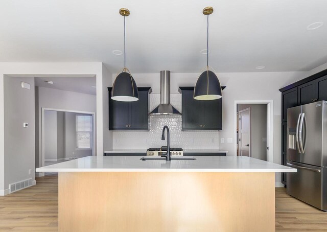 3620 Angelus Way, Cross Plains, WI 53528 - kitchen featuring light countertops, stainless steel fridge with ice dispenser, wall chimney range hood, visible vents, and light wood-style floors