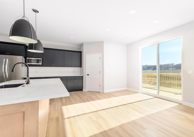 3620 Angelus Way, Cross Plains, WI 53528 - kitchen featuring light countertops, stainless steel appliances, a sink, light wood-style floors, and hanging light fixtures