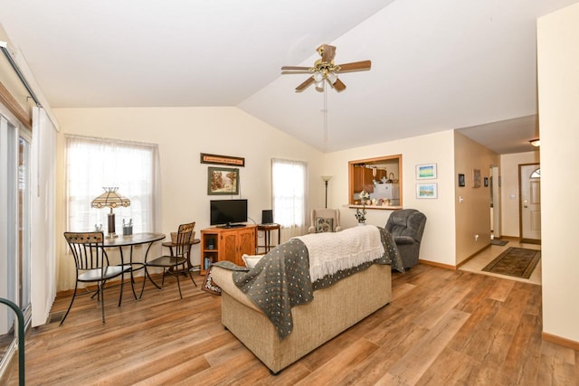 living room with light hardwood / wood-style floors, plenty of natural light, ceiling fan, and lofted ceiling