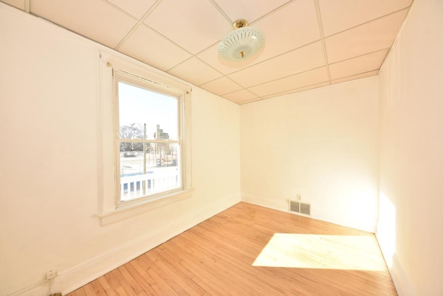 unfurnished room with a paneled ceiling and hardwood / wood-style flooring