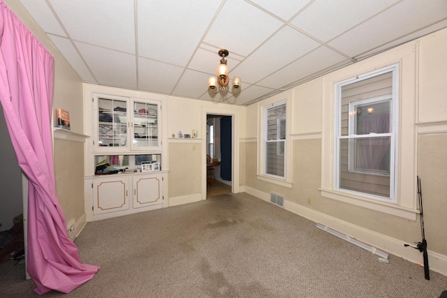 carpeted spare room with a paneled ceiling and a notable chandelier