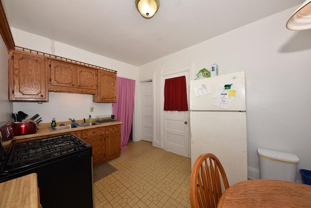 kitchen with black range oven, white fridge, and sink