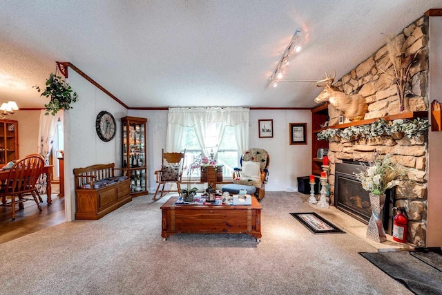 carpeted living room with a fireplace, a textured ceiling, track lighting, and ornamental molding