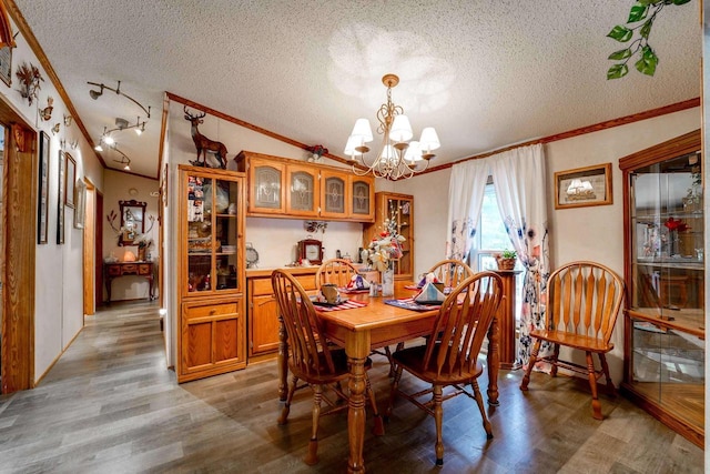 dining space with a notable chandelier, ornamental molding, a textured ceiling, and light hardwood / wood-style flooring