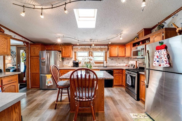 kitchen with a kitchen bar, ornamental molding, stainless steel appliances, and light wood-type flooring