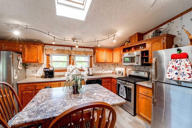 kitchen featuring a center island, a skylight, light wood-type flooring, a textured ceiling, and stainless steel appliances