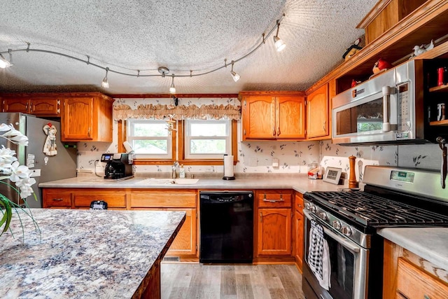 kitchen featuring a textured ceiling, light hardwood / wood-style floors, sink, and appliances with stainless steel finishes