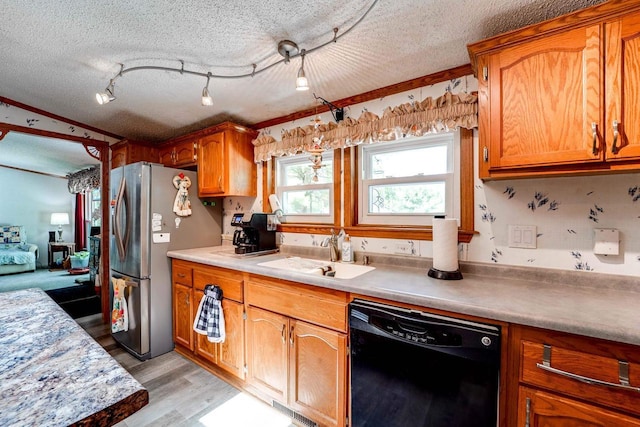 kitchen featuring stainless steel fridge, a textured ceiling, sink, dishwasher, and light hardwood / wood-style floors