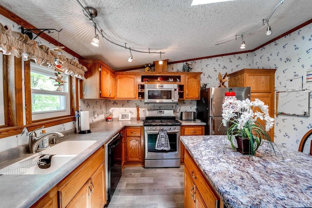 kitchen with ornamental molding, a textured ceiling, stainless steel appliances, sink, and hardwood / wood-style floors