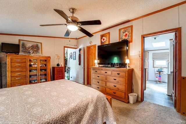 bedroom featuring crown molding, a skylight, ceiling fan, a textured ceiling, and light colored carpet