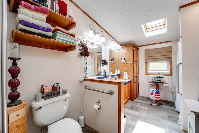 bathroom featuring a skylight, crown molding, hardwood / wood-style floors, a textured ceiling, and vanity