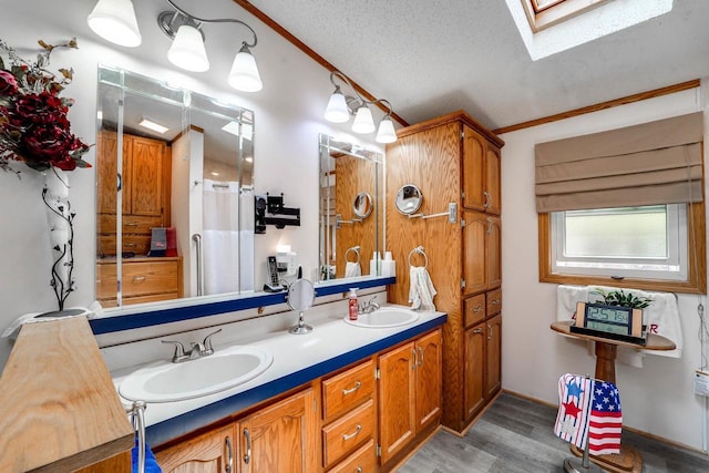 bathroom featuring a skylight, ornamental molding, vanity, a textured ceiling, and hardwood / wood-style flooring