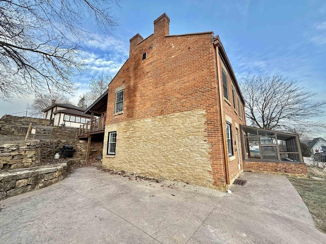 view of property exterior featuring a patio area and a sunroom