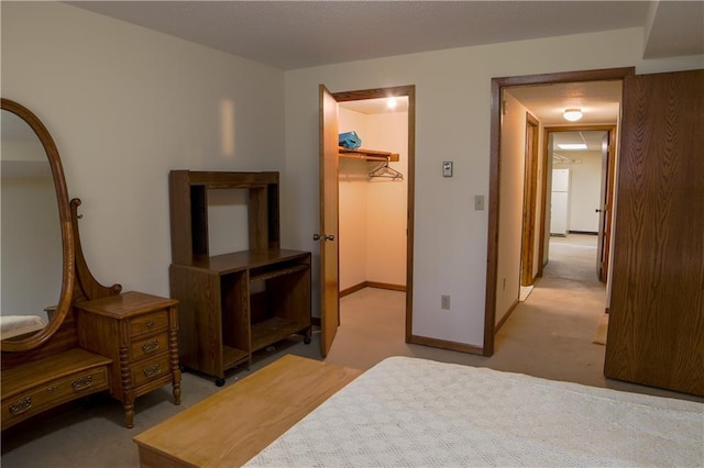 carpeted bedroom with a walk in closet, white fridge, and a closet