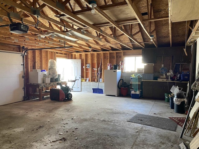 garage featuring white fridge and a garage door opener