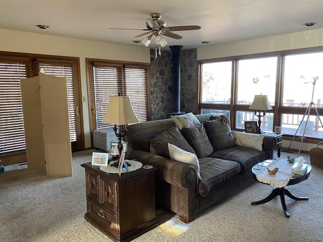 living room with light colored carpet, a wood stove, and ceiling fan