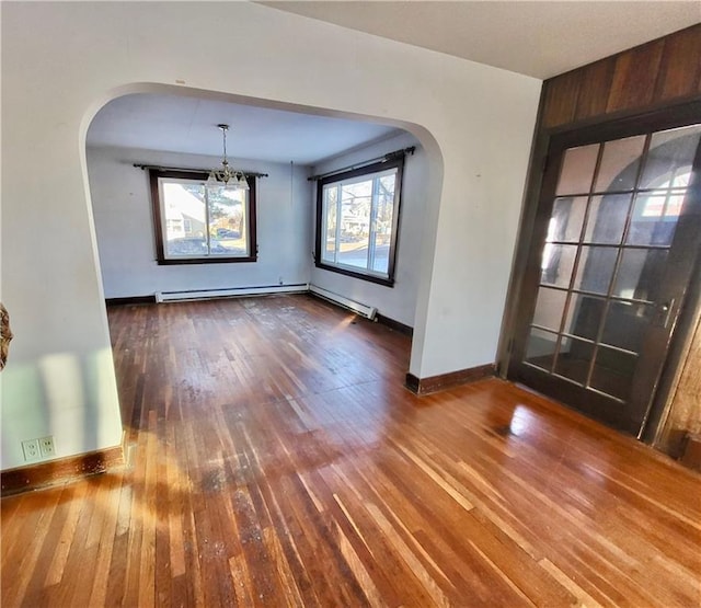 unfurnished dining area with dark hardwood / wood-style floors and a baseboard heating unit