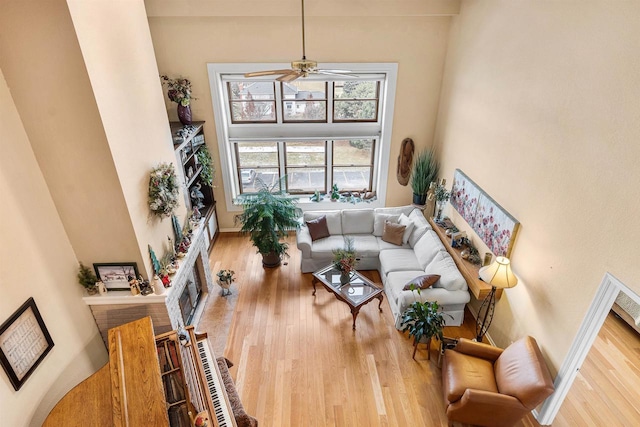 living room with ceiling fan, wood-type flooring, and a high ceiling