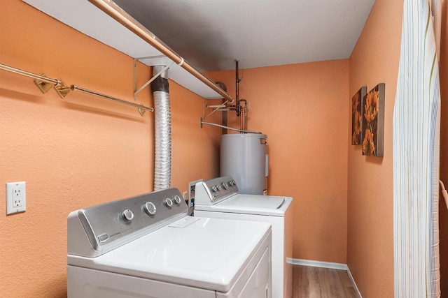 clothes washing area featuring water heater, hardwood / wood-style floors, and independent washer and dryer