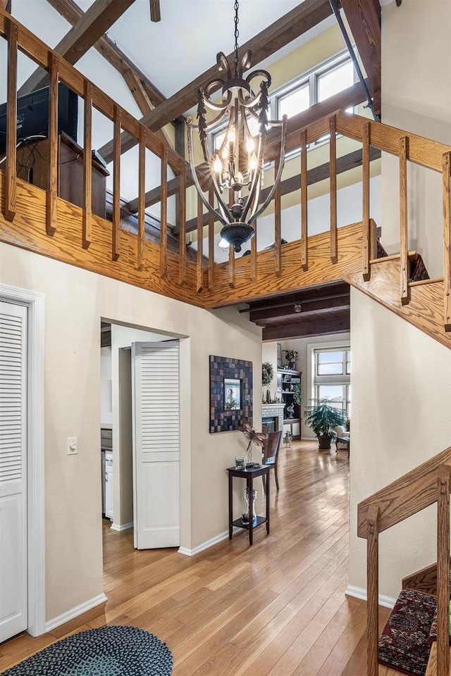 interior space featuring beamed ceiling, hardwood / wood-style flooring, an inviting chandelier, and a wealth of natural light