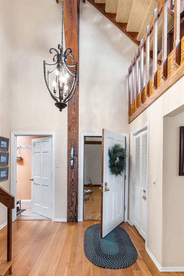 entrance foyer with hardwood / wood-style flooring, a towering ceiling, and a chandelier