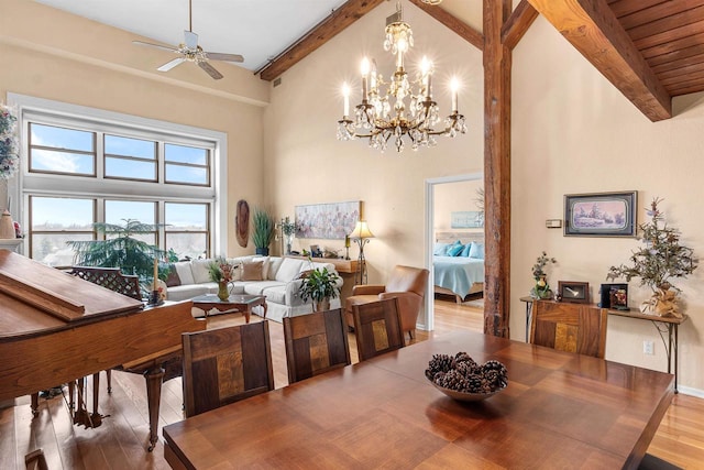 dining space featuring beamed ceiling, a towering ceiling, and light hardwood / wood-style flooring