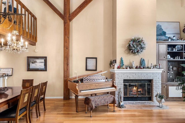 miscellaneous room with a high ceiling, hardwood / wood-style flooring, a fireplace, a notable chandelier, and beam ceiling