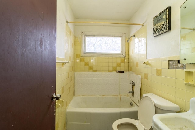 full bathroom with sink, tiled shower / bath, tile walls, and toilet