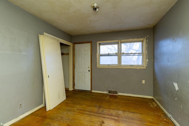 unfurnished bedroom with hardwood / wood-style floors and a closet